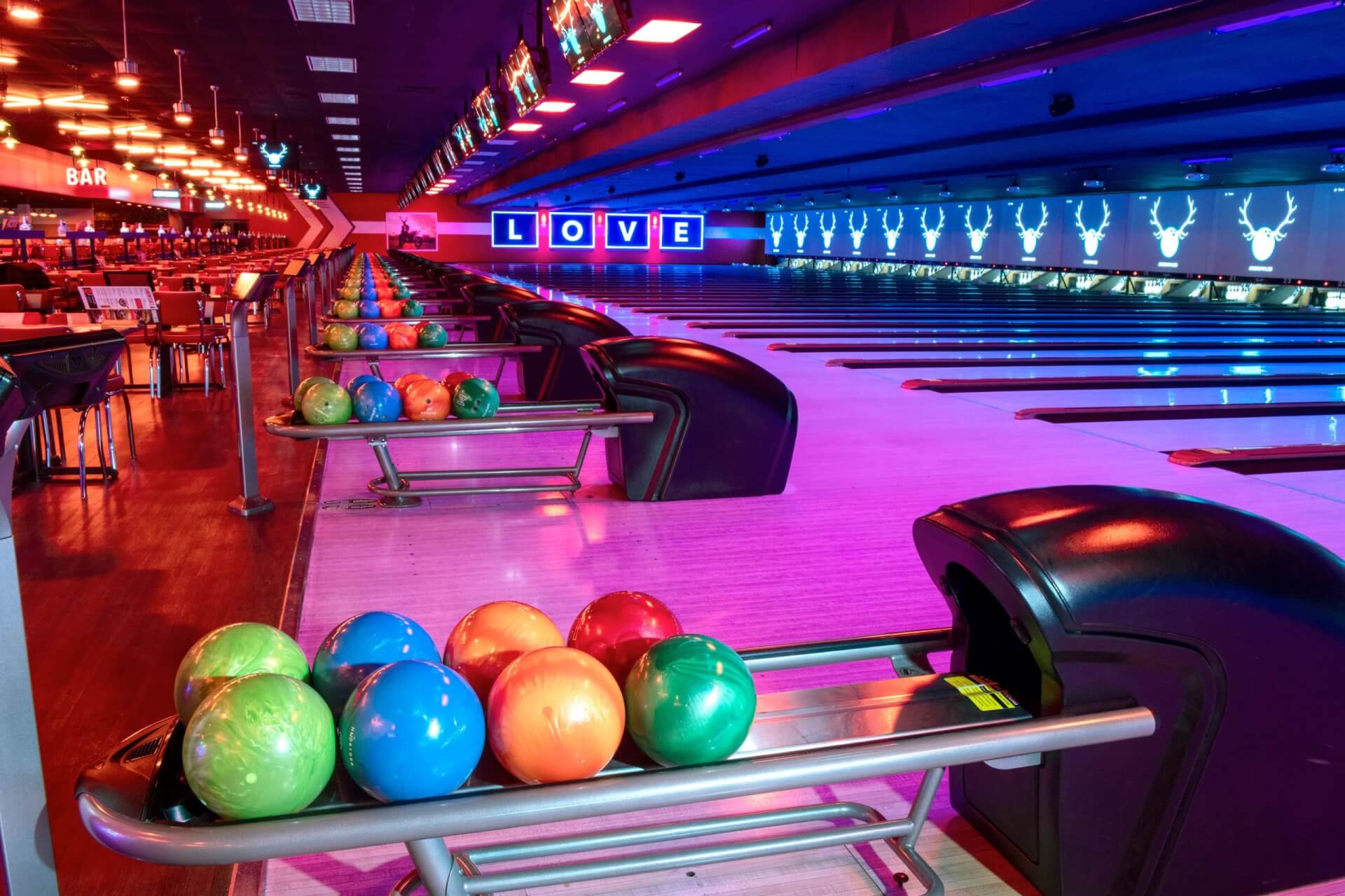 Bowling balls lined up on a rack near the lanes