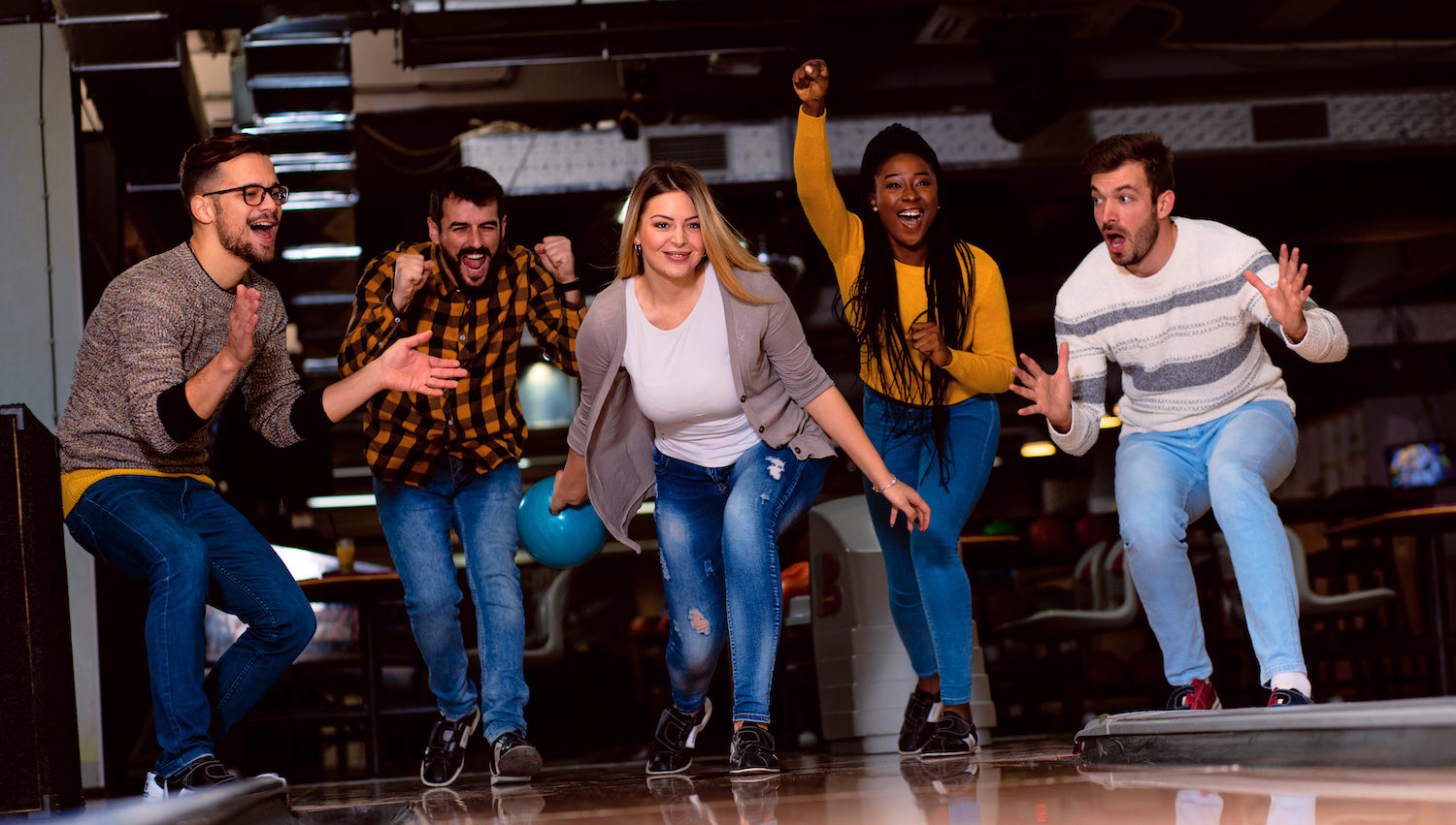 Friends celebrating a strike in a bowling lane